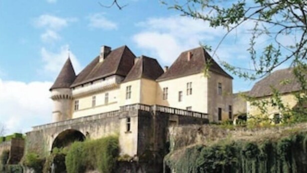 Un edificio histórico con una torre, un puente y un río.