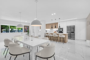 A modern kitchen with white cabinets, a central island, and a stainless steel refrigerator.