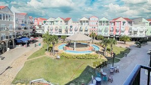 Une cour intérieure avec une piscine circulaire, des espaces de détente en plein air et, en arrière-plan, des bâtiments aux couleurs vives.
