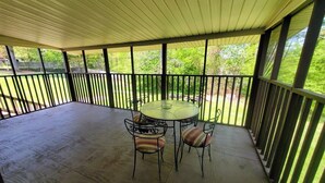 A covered patio with a round table and chairs, surrounded by a railing. - Freshly Renovated Douglasville Home (Douglasville)