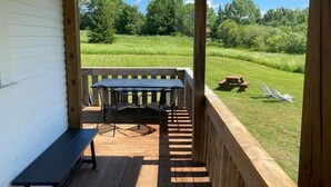 A covered outdoor area with a wooden deck, a table with chairs, and a bench.
