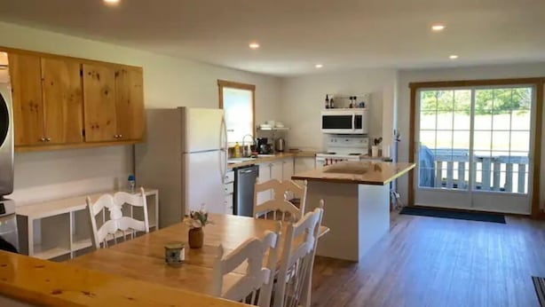 A kitchen with wooden cabinets, a dining table with chairs, a microwave, and a stove.