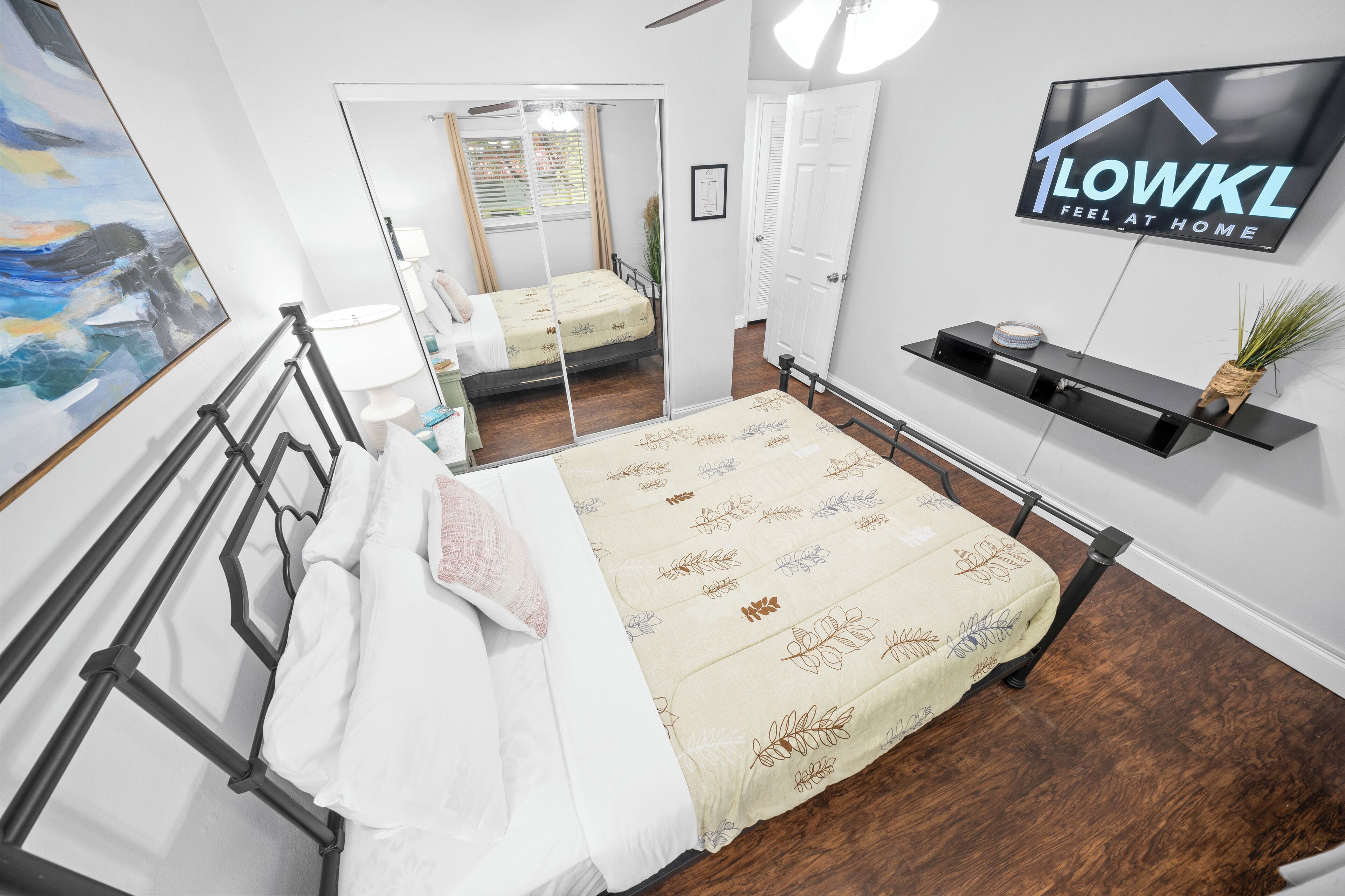 Ein Schlafzimmer mit einem Bett, einem Fernseher, einem Spiegel und einem Fenster.
