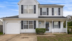 A two-story house with a garage, a front porch, and a small front yard. - 15 mins from the beach (Virginia Beach)