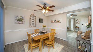 A dining area with a wooden table, chairs, a ceiling fan, and wall-mounted potted plants. - 15 mins from the beach (Virginia Beach)