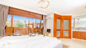 Een ruime slaapkamer met een groot bed, een televisie en uitzicht op de omgeving.