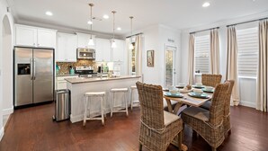 A modern kitchen with white cabinets, stainless steel appliances, and a central island with bar stools.