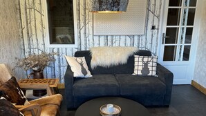 A cozy living room with a dark blue sofa, a round coffee table, and a fireplace.