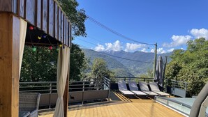 A wooden deck with lounge chairs and a view of mountains.