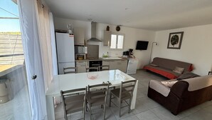 A compact living space with a dining table, chairs, a sofa, and a kitchenette. - SYRAH Single-Story Villa in a Farming Village in the Gard, Between the Sea and the Cévennes, Air Conditioning, Parking Available (Combas)