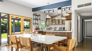 Una cocina moderna con una isla central, electrodomésticos integrados y un comedor con sillas de mimbre.