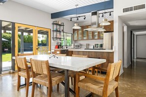 Una cucina moderna con isola centrale, elettrodomestici integrati e un'area pranzo con sedie in vimini.