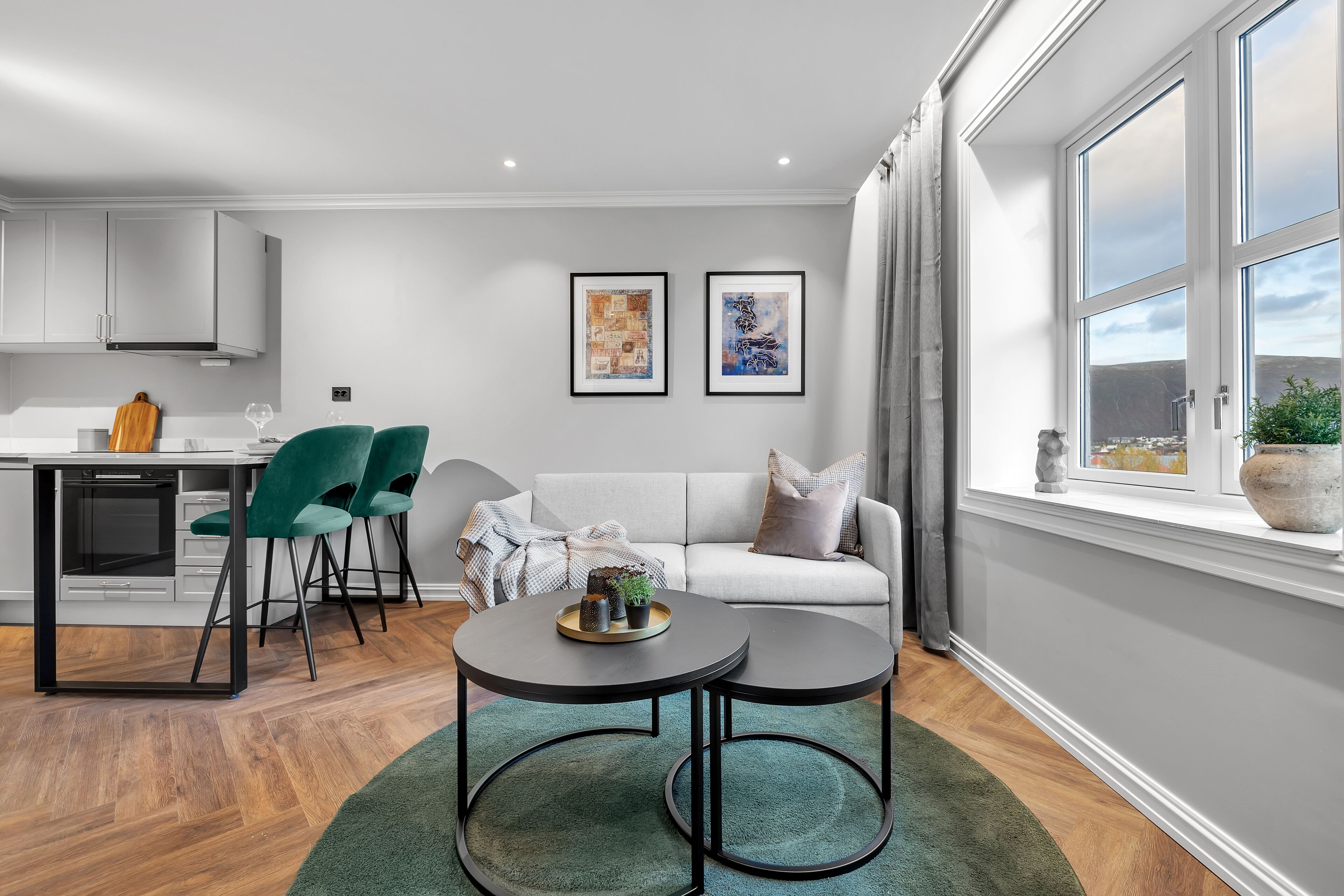 Un salon moderne comprenant un canapé, deux fauteuils, une table à manger et des œuvres d’art accrochées au mur.