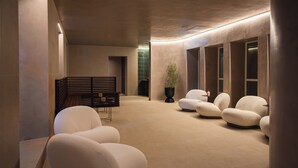 Et moderne spa-område med buet loft, beige vægge og et siddeområde med hvide stole.