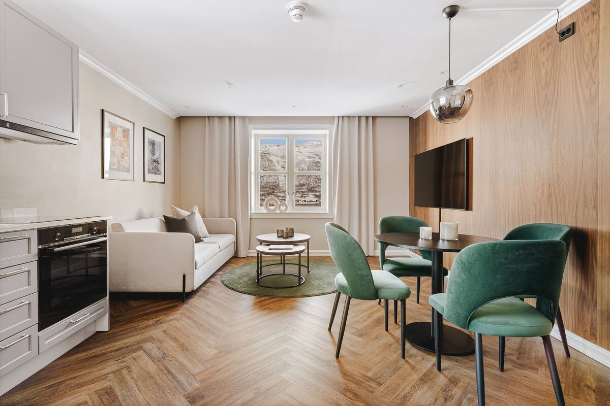 A modern living room with a sofa, dining table, chairs, and a TV.