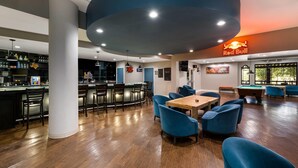 Un espacio interior amplio con bar, asientos y mesa de billar.