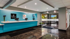 Un mostrador de recepción con superficie azul, un cartel de 'Clarion by Choice Hotels' y un cartel de 'Suburban Studios'.