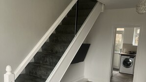 A modern interior with a staircase, a kitchen area, and a dining space. - Modern welsh cottage (penygraig)