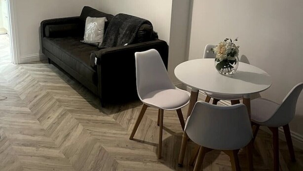 A modern living room with a black sofa, white chairs, and a round table. - Modern welsh cottage (penygraig)