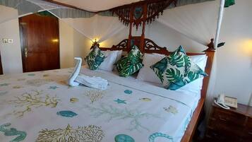 A bed with a canopy, a bedside telephone, and a nightstand.