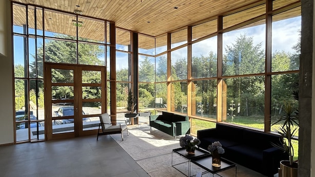 A spacious room with large windows, a wooden ceiling, and a modern seating area. - Mawün Lodge (Villarrica)