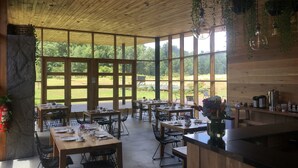 A spacious dining area with large windows, wooden ceiling, and modern furniture. - Mawün Lodge (Villarrica)