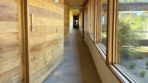 A hallway with wooden paneling, a door labeled '101', and large windows offering a view of greenery. - Mawün Lodge (Villarrica)