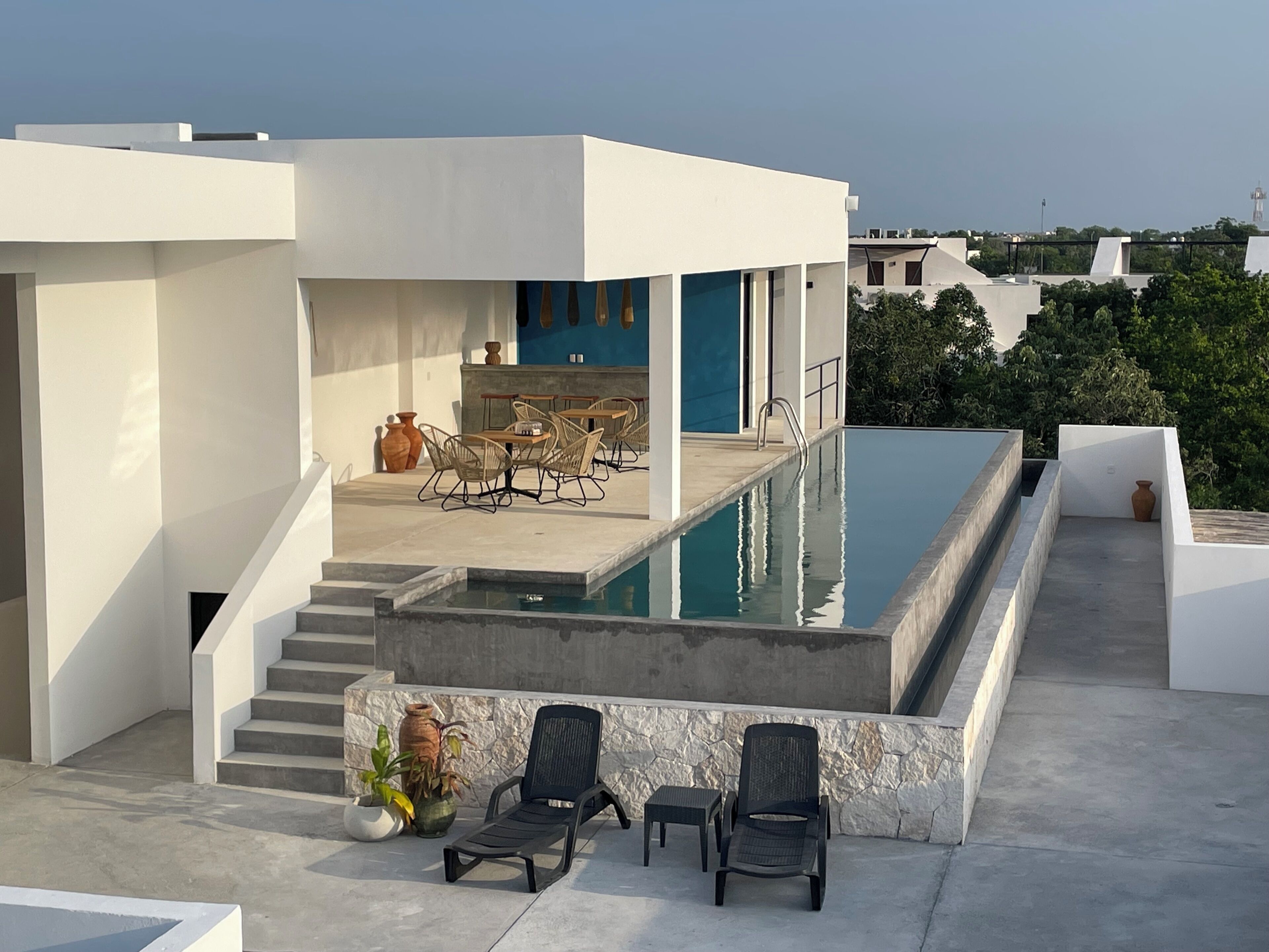 A modern outdoor pool area with a staircase leading to a covered seating area.