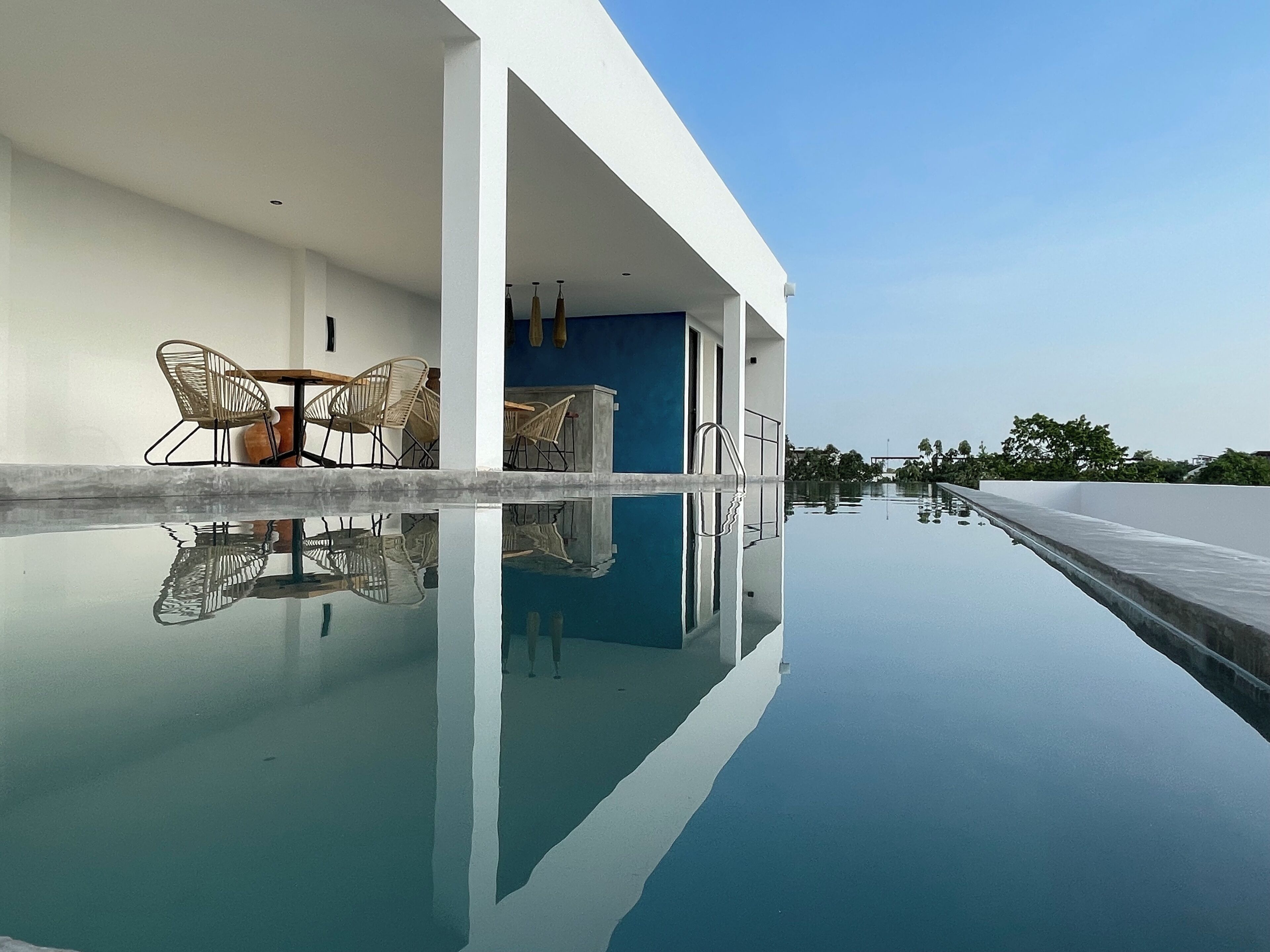 A modern pool area with clear water, white walls, and a blue accent wall.