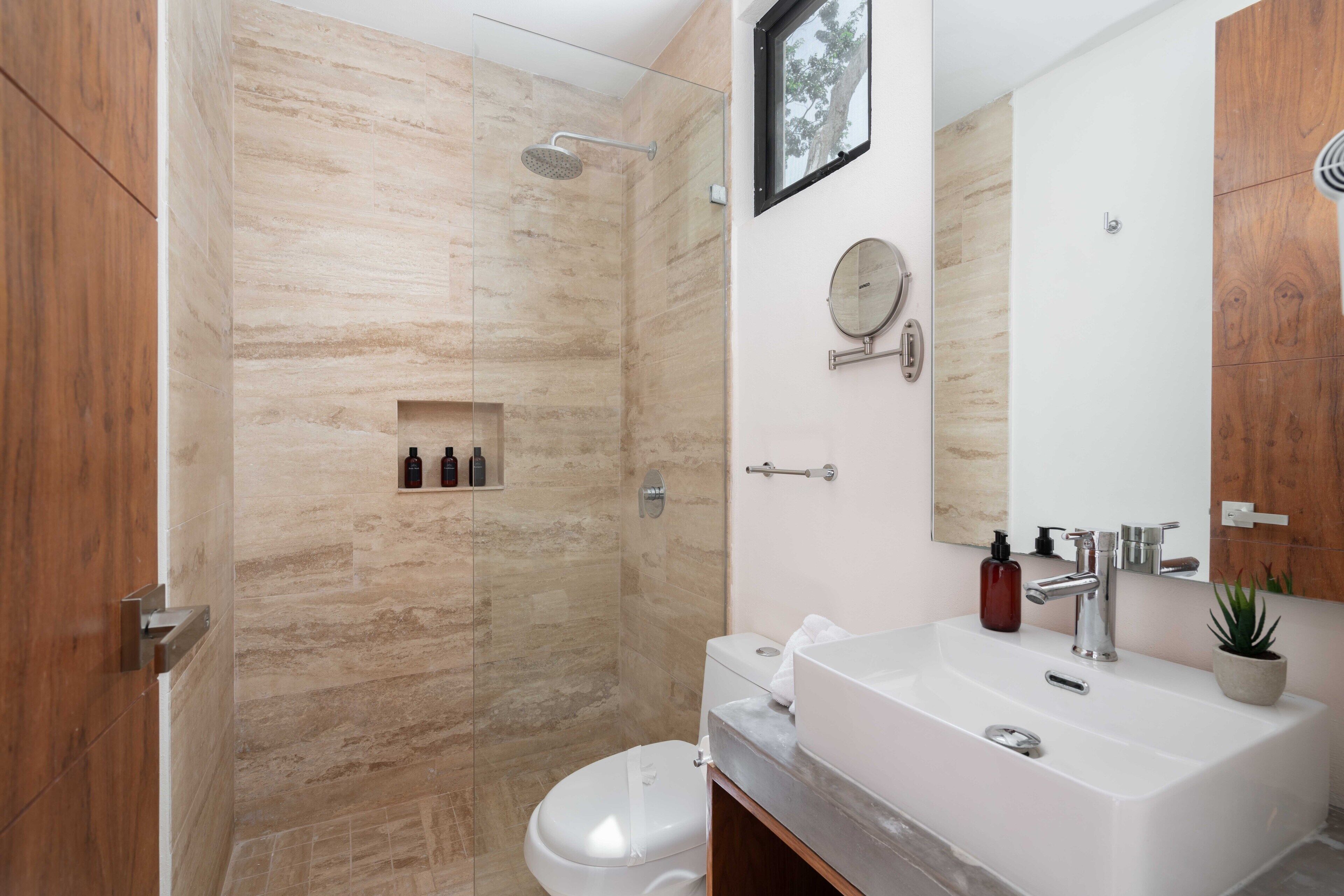 A modern bathroom with a glass-enclosed shower, a white sink, and a wooden vanity.