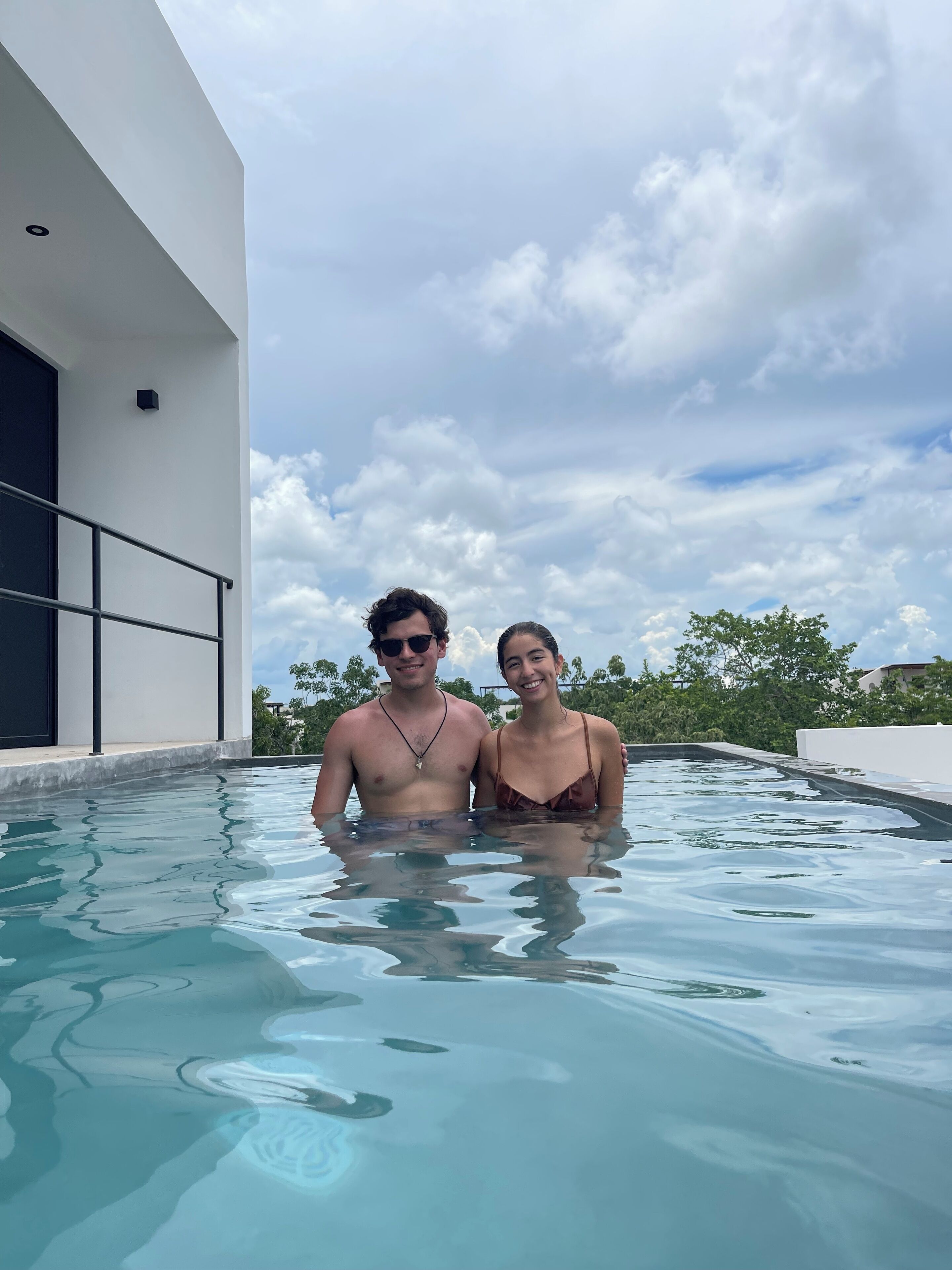 Una pareja en una piscina con un edificio moderno al fondo.