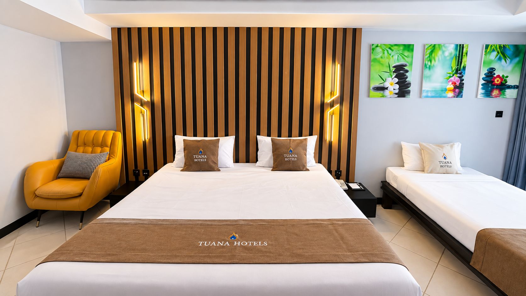 Una habitación de hotel con una cama grande, una mesita de noche, una silla y una obra de arte en la pared.