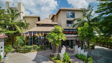 Un hotel con fachada moderna, acceso cubierto y un jardín ajardinado.