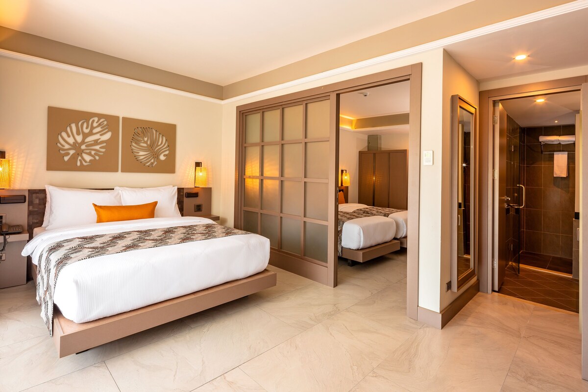 A modern hotel room with a large bed, a walk-in closet, and a separate bathroom.