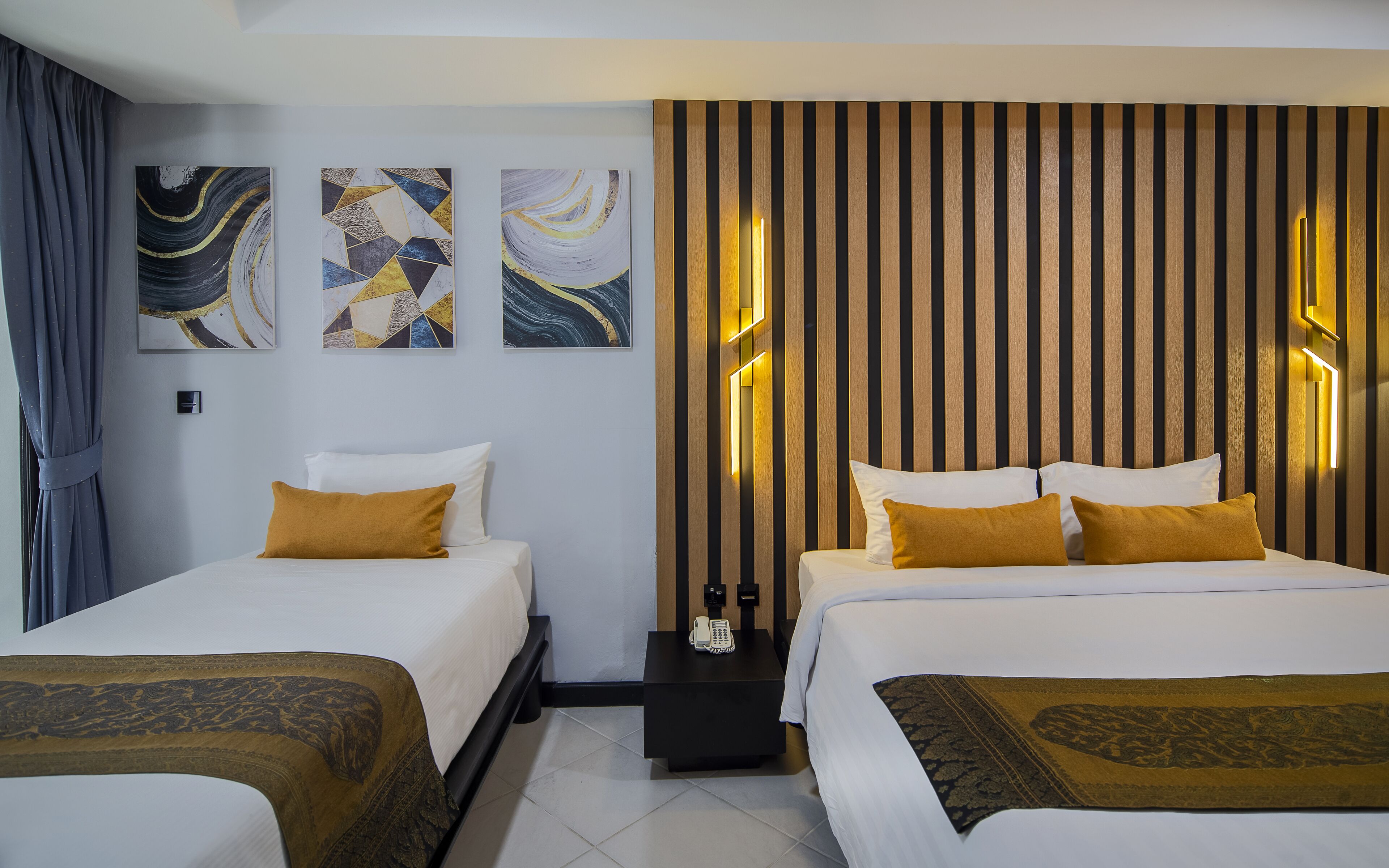 A hotel room with two beds, a nightstand, and abstract artwork on the walls.