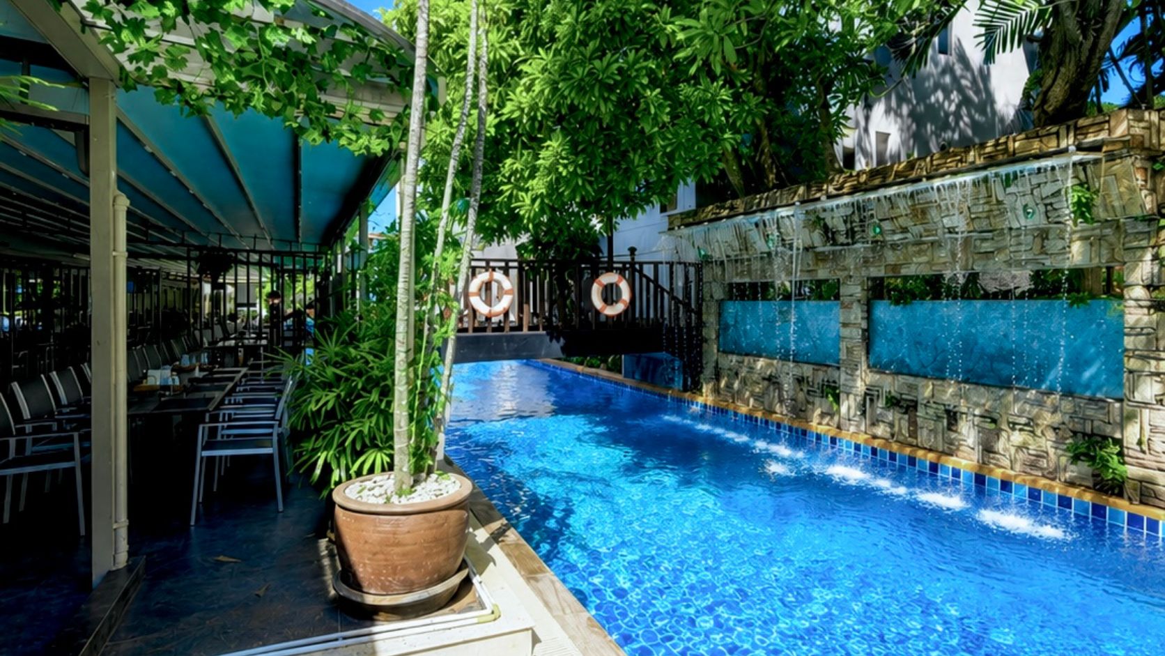 Une piscine intérieure avec un mur en pierre et un espace détente équipé de chaises.