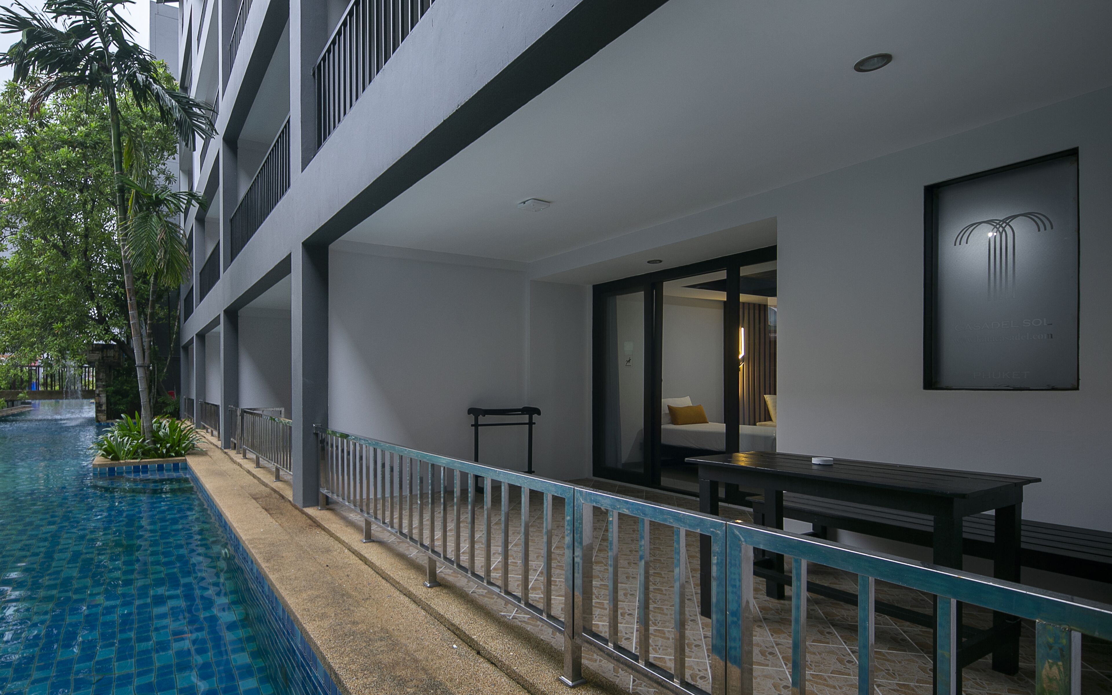 A hotel balcony with a pool, a dining table, and a chair.
