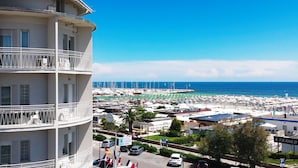 Un hotel frente al mar con varios pisos, un puerto deportivo con numerosos barcos y una vista despejada del océano.