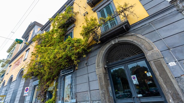 A building with a yellow facade, arched windows, and a sign reading 'ANGELASOLIA.' - Cozy Studio in Chiaia District by Wonderful Italy (Naples)