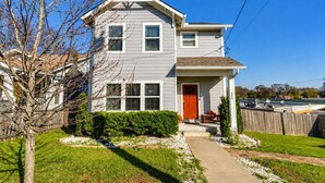 A two-story house with a front porch, a red door, and a mailbox.