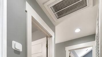 A hallway with wooden flooring, white doors, and a ceiling vent.