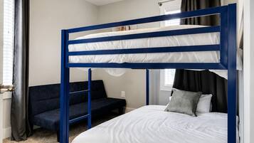 A bunk bed with a ceiling fan, a sofa, and a window with curtains.