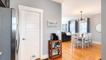 A modern kitchen with a refrigerator, a dining area with a table and chairs, and a living room with a sofa and a coffee table.