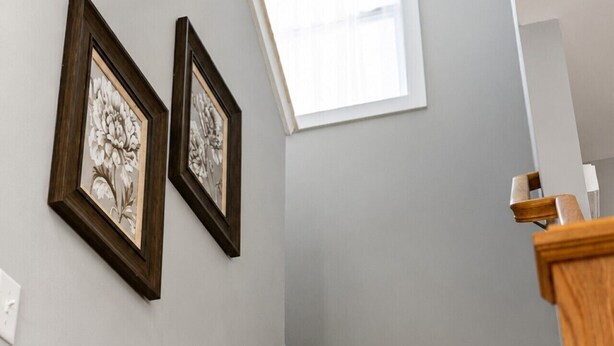A staircase with wooden handrails and a white wall.