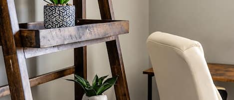 A wooden ladder shelf with plants and a book titled 'Talking to Strangers' against a wall.