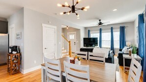 A modern living room with a dining area, a kitchen, and a staircase leading to another level.