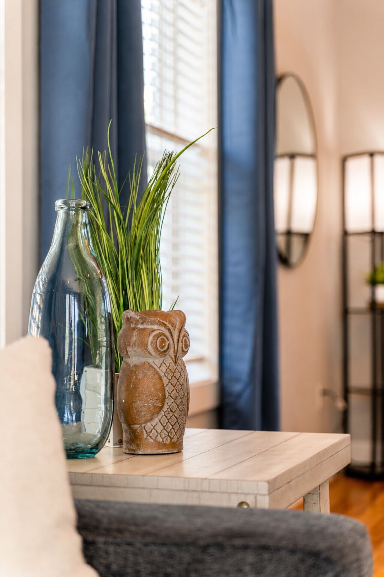 Ein Zimmer mit einem Tisch, auf dem sich eine Vase mit Grünpflanzen und eine tönerne Eule befinden.