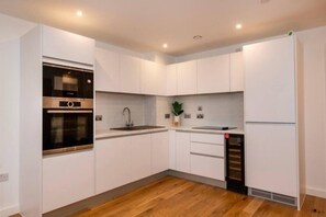 A modern kitchen with white cabinets, a built-in oven, a sink, and a refrigerator. - 1 Bed in Birmingham City Center (Birmingham)