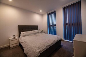 A bedroom with a bed, a nightstand, a dresser, and a window with blinds. - 1 Bed in Birmingham City Center (Birmingham)