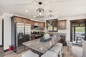 A modern kitchen with stainless steel appliances, granite countertops, and pendant lighting. - Pet friendly Embers Ultimate duplex, hot tub, wifi, paved roads, pool access (Lead)